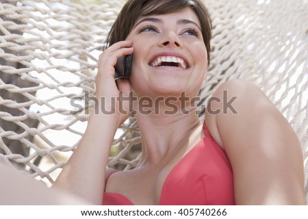 A woman lying in a hammock chatting on a mobile phone