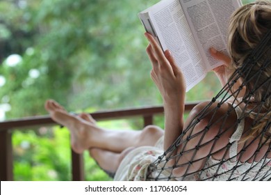 Woman lying in a hammock in a garden and enjoying a book reading - Powered by Shutterstock