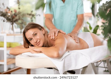 Woman lying at massage table during deep tissue back massage - Powered by Shutterstock