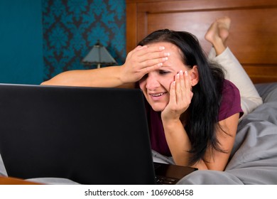 Woman lying on bed and looking at computer. - Shutterstock ID 1069608458