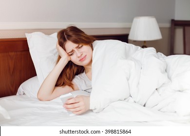 Woman lying on bed looking unhappy with a text message - Shutterstock ID 398815864