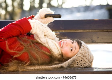 Woman Lying On Bench With Mobile Phone