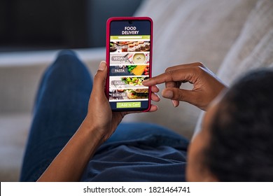 Woman lying on couch using food delivery app on smartphone. Close up of african woman hands holding cellphone and ordering food online. - Shutterstock ID 1821464741