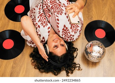 Woman lying on floor with headphones , vinyl records and phone.  - Powered by Shutterstock