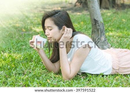 Woman lying on grass field with a cup of coffee in the park