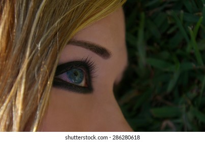 A Woman Lying On Grass With Smokey Eye Makeup