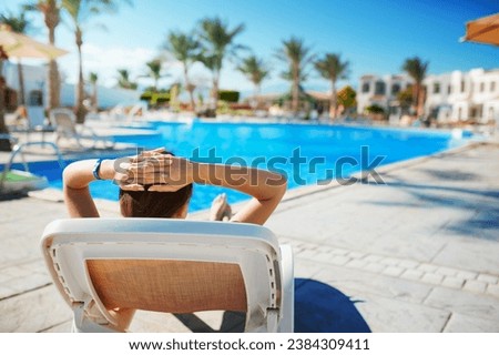 woman lying on a a lounger and looking the pool.