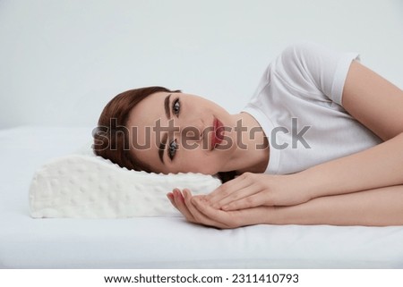Woman lying on memory foam pillow against white background