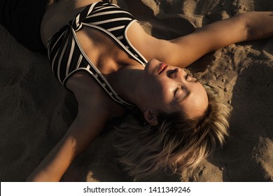 Woman lying on the sand in a relaxed state with eyes closed