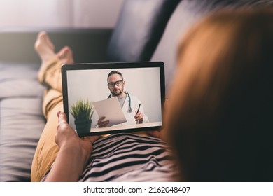 Woman lying on a sofa and talking with a doctor online using digital tablet. Telemedicine concept.