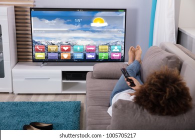 Woman Lying On Sofa Watching Television With Colorful Applications On Screen