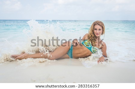 woman lying on white sand beach and plashing with waves. concept about summer,vacations,islands, beauty and fashion, and people