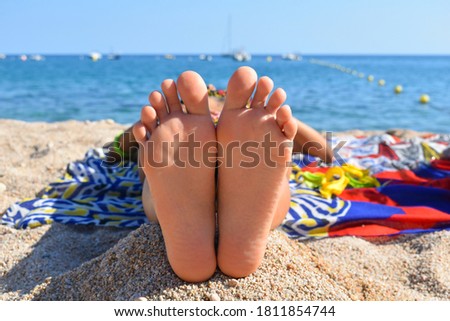 Woman lying in the sun with her feet facing the camera and her head towards the sea, vacation.
