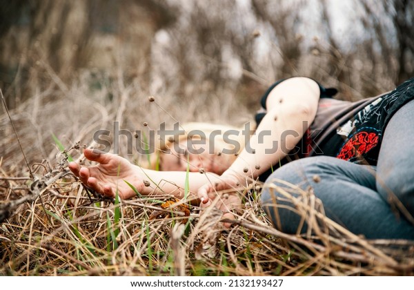 Woman lying\
unconscious in the autumn grass. Selective focus on hands. Close up\
dead female person in\
nature