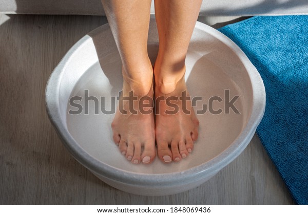 Woman made bath with hot\
water and baking soda for his feet. Homemade bath soak for dry feet\
skin
