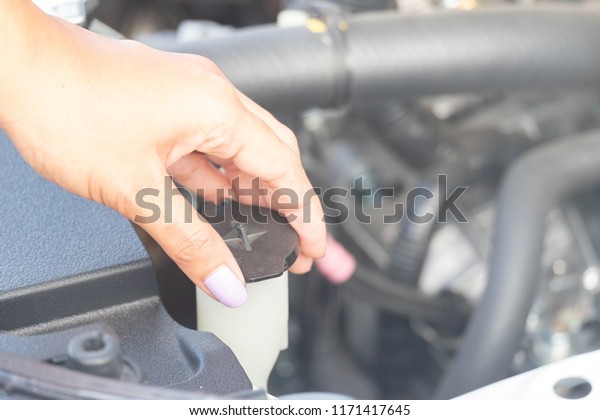 a\
woman maintenance a car.  Check the car\'s water\
level.