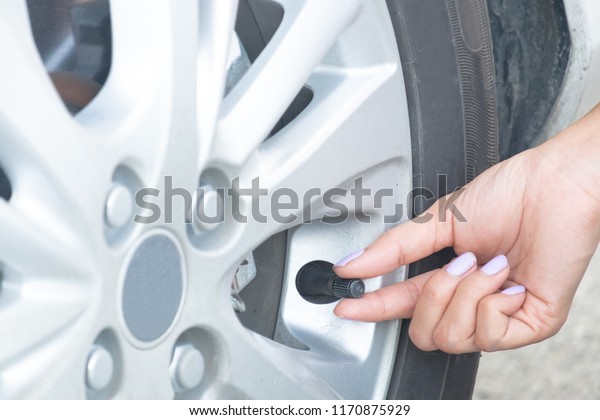 a\
woman maintenance a car.  Check the tire\
pressure.