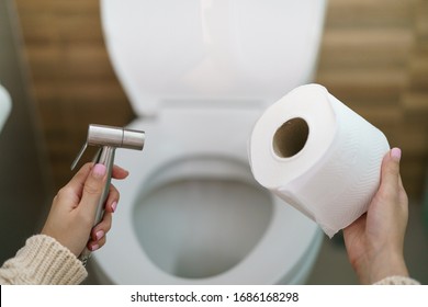 Woman make a choice, bidet shower or toilet paper.