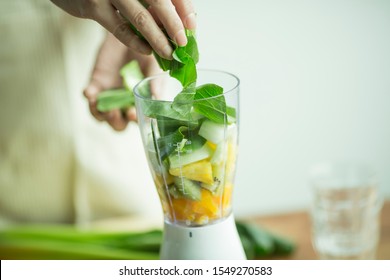 Woman to make a green smoothie in the mixer