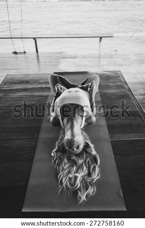 Woman make morning yoga exercise on the wooden terrace, matsiasana pose, black and white photo
