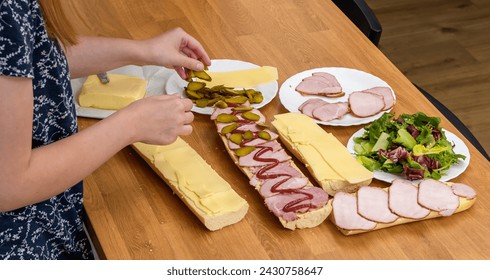 A woman makes breakfast sandwiches with cheese and sliced ​​ham - Powered by Shutterstock