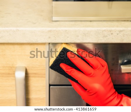 Woman makes chores in the kitchen at home, cleaning in gloves with a sponge. Cropped view. cleaning service