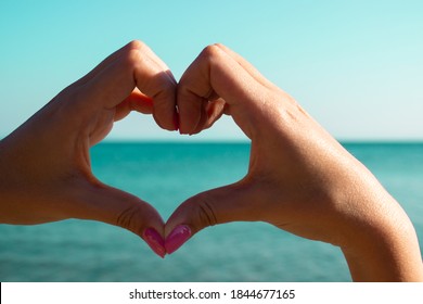 Woman Makes Heart Symbol With Her Hand. Love Concept. Colorful Nail Art. Pink Nail Polish. Valentines Day Concept. Valentine's Day Background