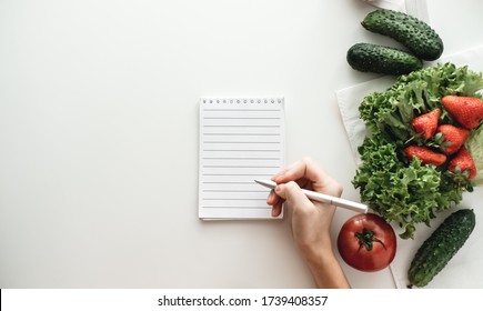 Woman Makes Notes In A Notebook, Food Shopping List Or Writing Recipes. Copy Space. Flat Lay