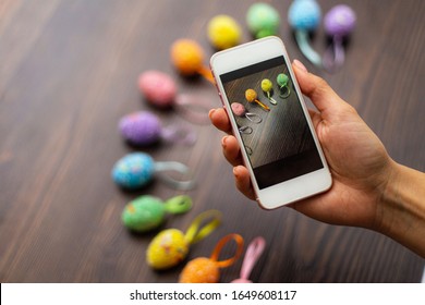 Woman makes a photograph of the colorful easter eggs with her cell phone. Mobile photo. Copyspace and place for text and wording. Easter concept - Powered by Shutterstock