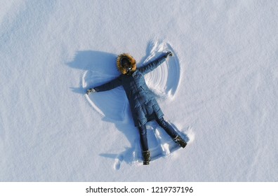 Woman Makes Snow Angel Laying In The Snow. Top View. Aerial Foto.