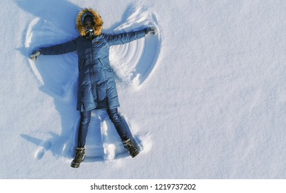 Woman Makes Snow Angel Laying In The Snow. Top View. Aerial Foto.