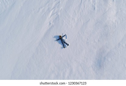 Woman Makes Snow Angel Laying In The Snow. Top View. Aerial Foto.