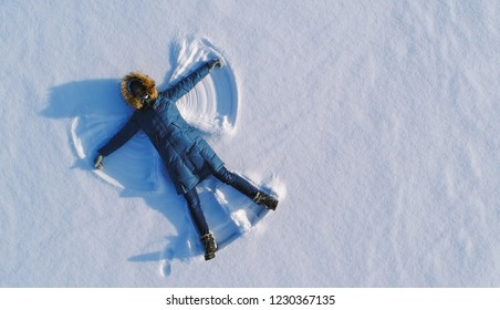 Woman Makes Snow Angel Laying In The Snow. Top View. Aerial Foto.