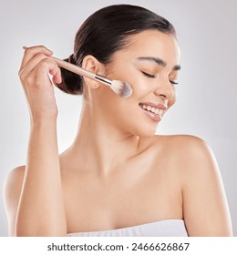 Woman, makeup brush and smile in studio for blush, cosmetics and application on white background. Female person, beauty and tools with happiness for highlight, contour and skincare with eyes closed