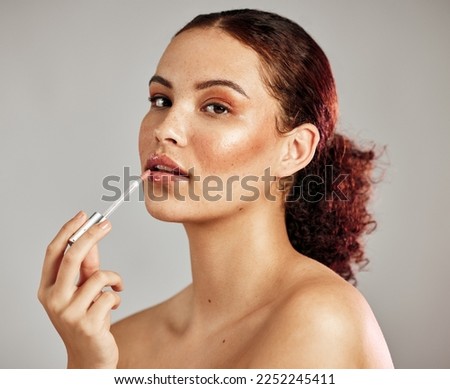 Woman, makeup portrait and lip gloss application for beauty, cosmetics dermatology and skincare wellness in grey background. Female model, face and lipstick brush or lip balm product for self care
