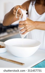 Woman Making Almond Milk At Home, Squeezing The Cheese Cloth To Filter It. A Vegan Healthy Option.