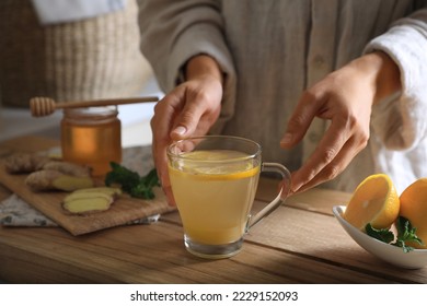 Woman making aromatic ginger tea at wooden table indoors, closeup - Powered by Shutterstock