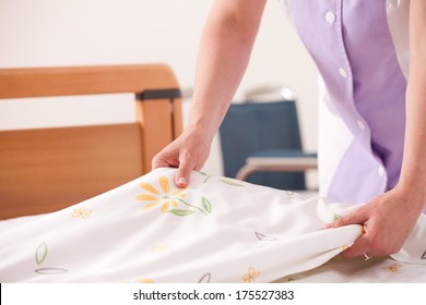 Woman Making Bed And Changing Bedding In Guest Room.