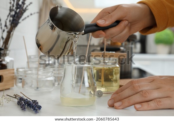 Woman making
candles at white table,
closeup
