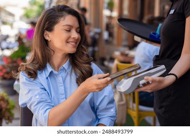 Woman making a cashless payment at a cafe using the NFC technology on her smartphone - Powered by Shutterstock - Get 15% off with code: PIKWIZARD15