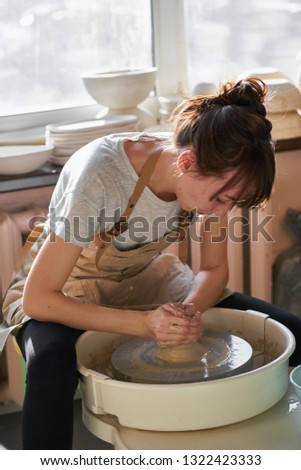 Similar – Young female sitting by table and making clay or ceramic mug