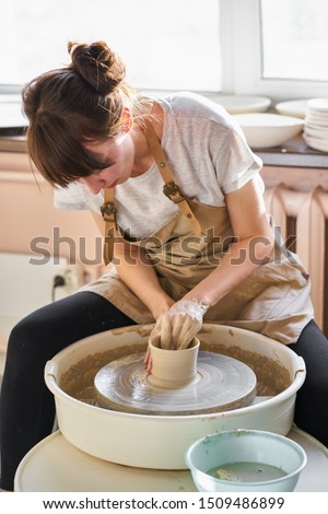 Similar – Young female sitting by table and making clay or ceramic mug