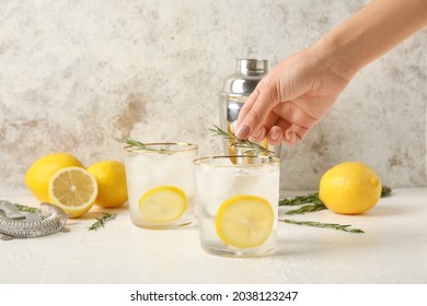 Woman making cold gin tonic on light background