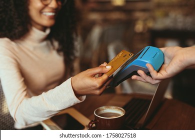 Woman making a contactless card payment in a coffee shop. Female customer paying using her credit card in a cafe.