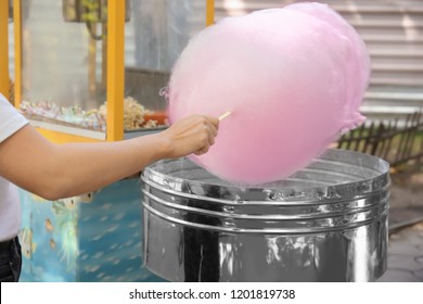 Woman making cotton candy in floss machine outdoors