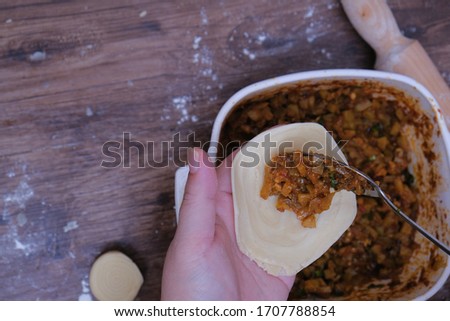 Woman making curry puff on wooden table.