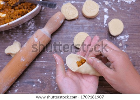 Woman making curry puff on wooden table.