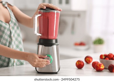 Woman making delicious smoothie with blender at white marble table in kitchen, closeup - Powered by Shutterstock