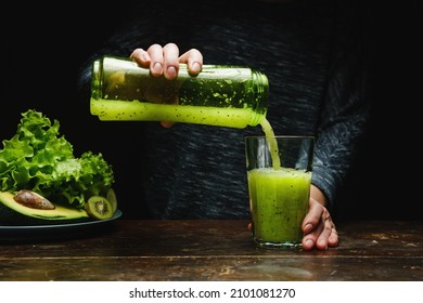 Woman making detox smoothie at home. Green food does the body good - Shutterstock ID 2101081270