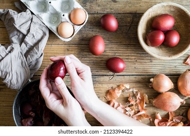 Woman making dyed Easter eggs painted with natural dye onion on wooden background. Process of dyeing eggs with natural paints for Easter. Natural ecological staining with food coloring. Top view.